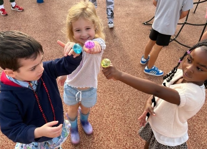 Three young students on the playground showing off colorful toy rings